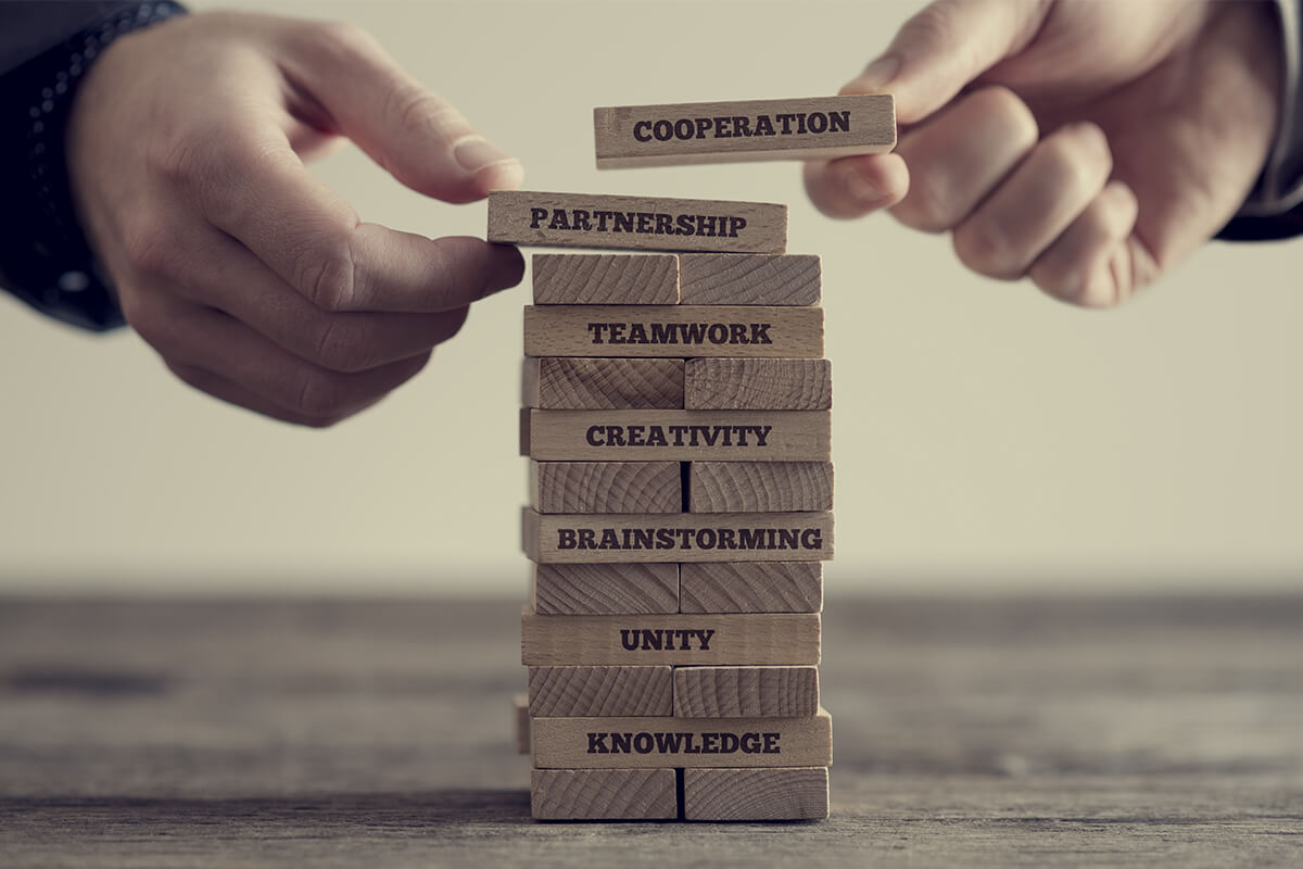 Photograph of two hands stacking blocks that say Cooperation and Partnership