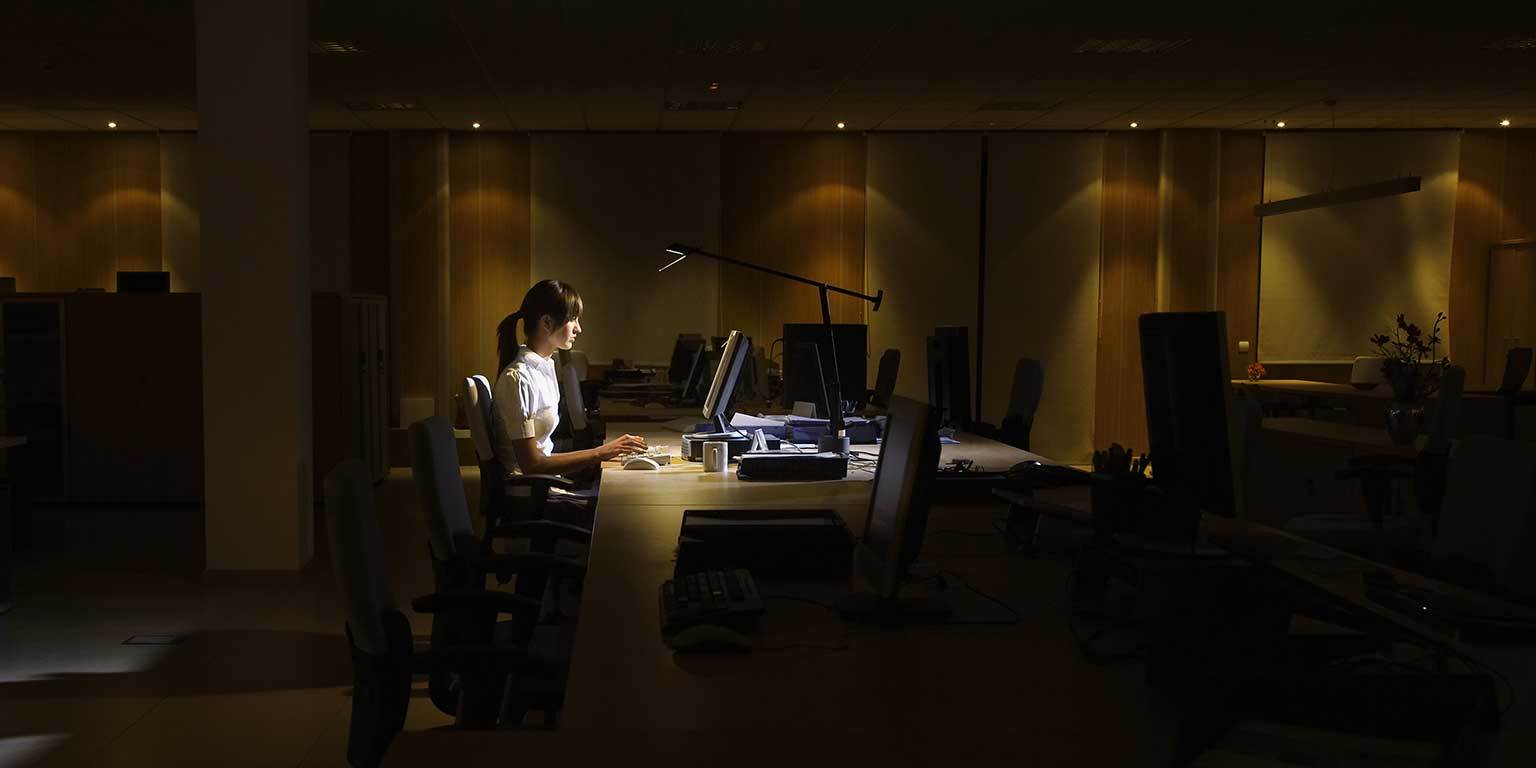 Photograph of a sales rep working at a desk in a dark empty office