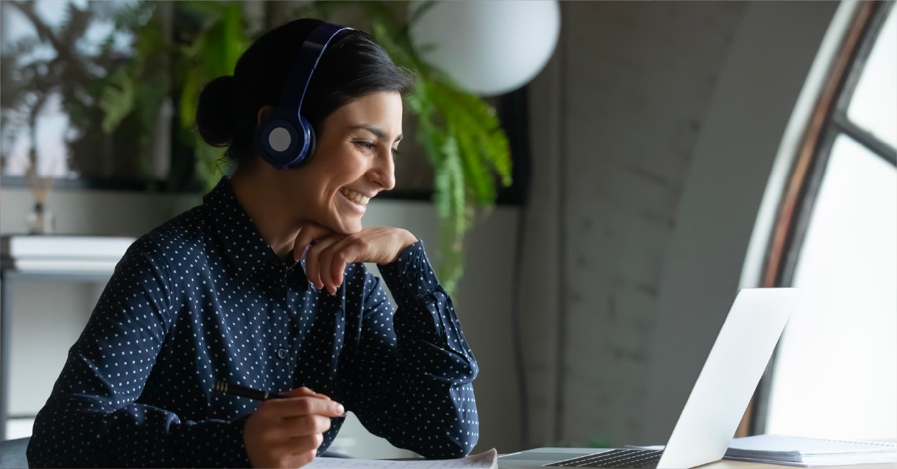 Photograph of a sales rep on a discovery call wearing headphones smiling at a laptop