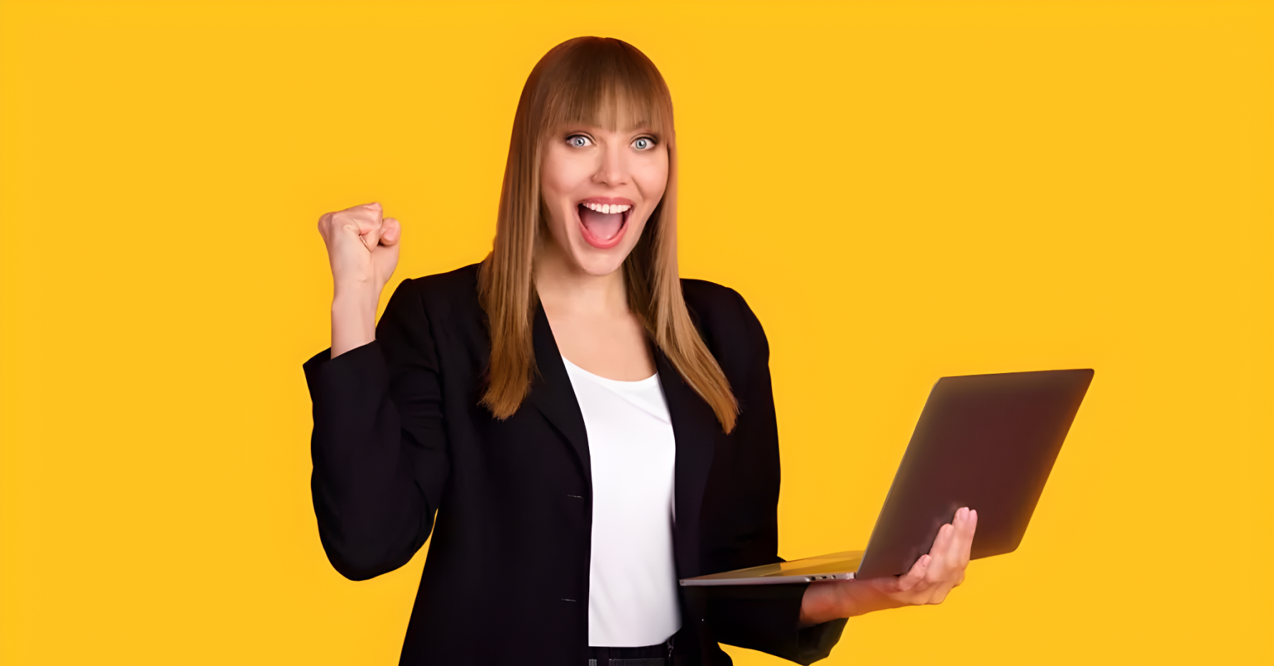 Photograph of a sales leader raising a fist in excitement and holding a laptop