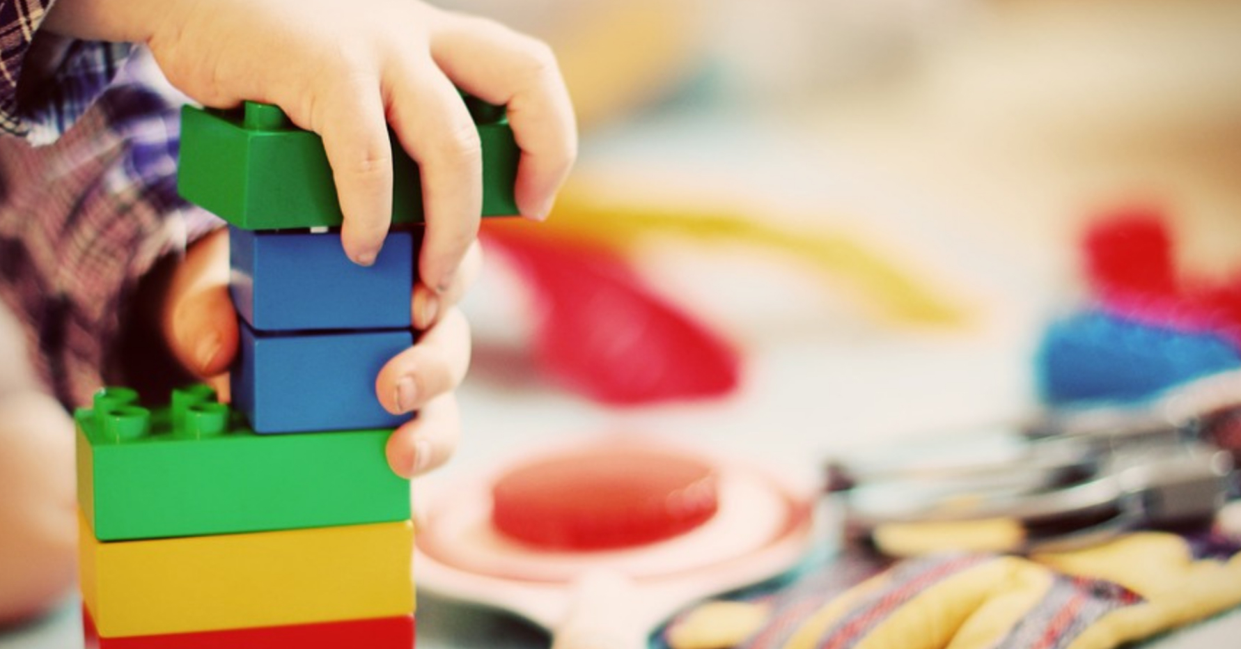 A child's hands building with Lego blocks