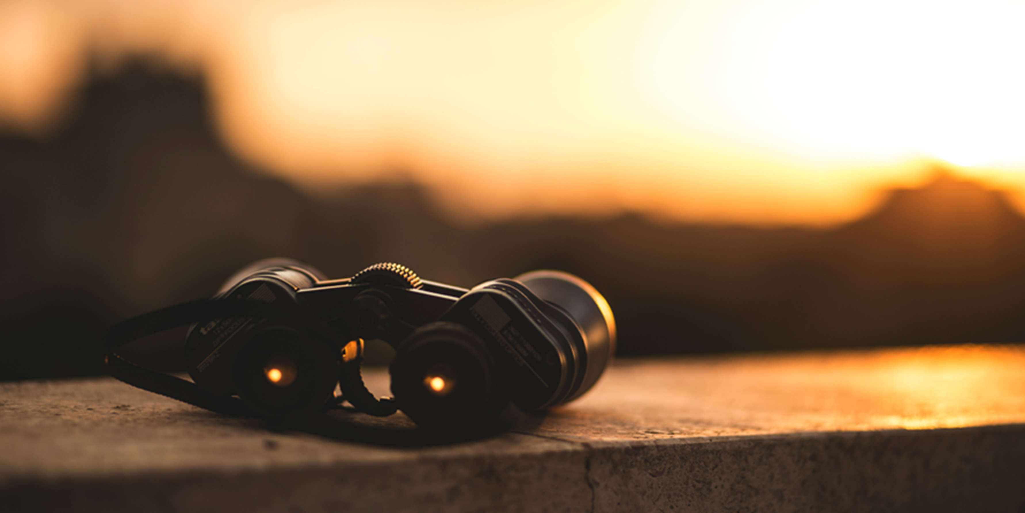 Photograph of a pair of binoculars on a wall at sunset