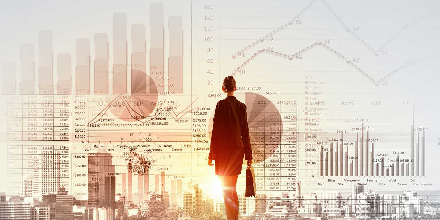 Stylized photograph of a business professional looking over cityscape overlapping images of line graphs and bar charts