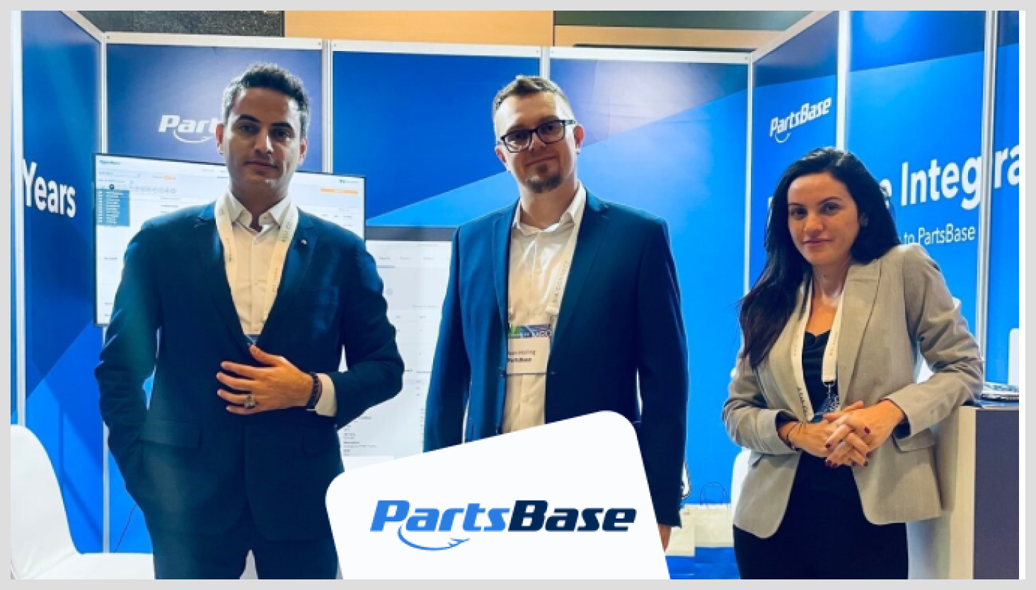 Three PartsBase employees in a PartsBase booth with suits on