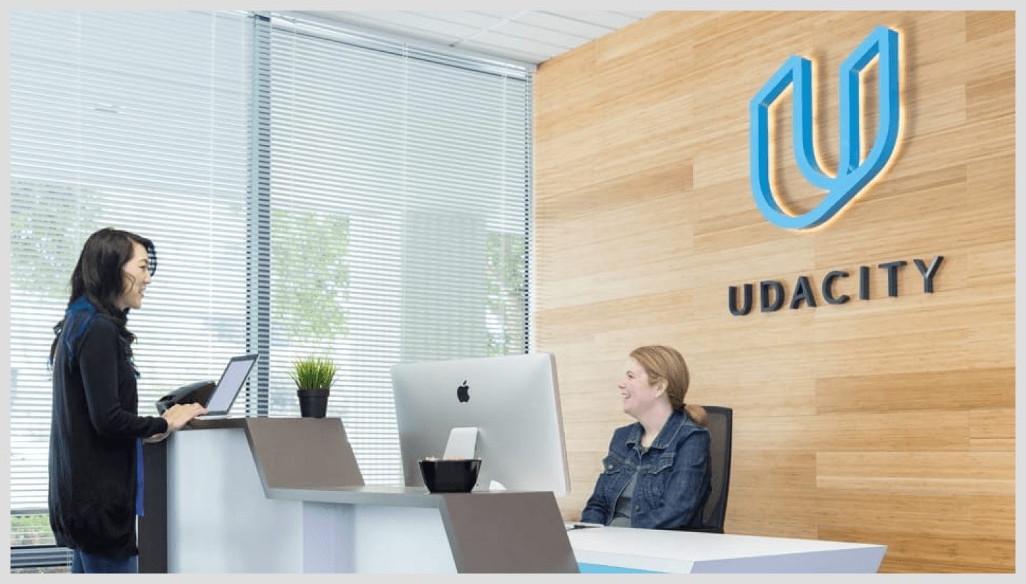 Two women in the Udacity lobby front desk area