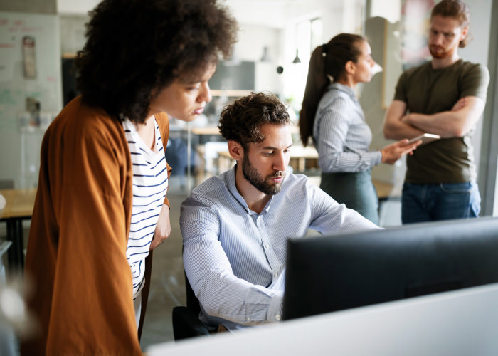 Photograph of a revenue team checking a Clari report on a computer