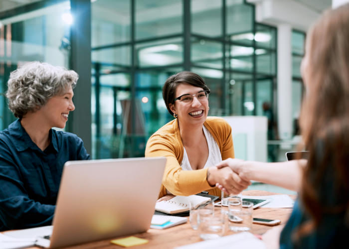 Photograph of a sales leader shaking a customer's hand across a conference table