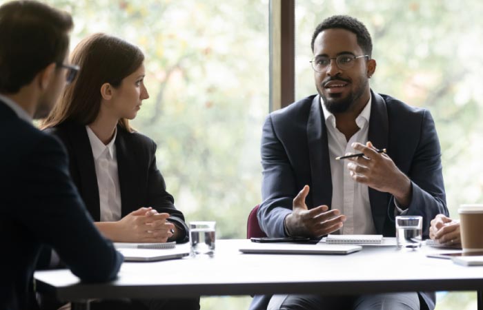 Photograph of three revenue leaders talking at a conference table