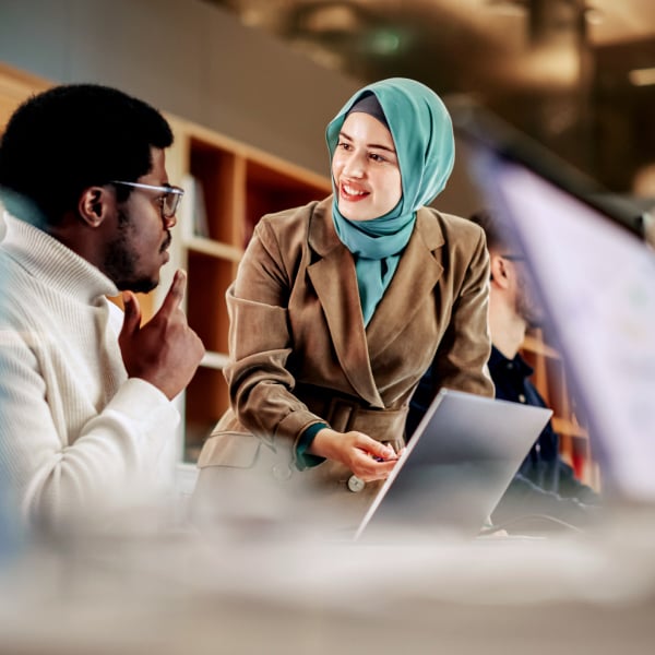 Photograph of two revenue professionals discussing a Clari report on a laptop screen